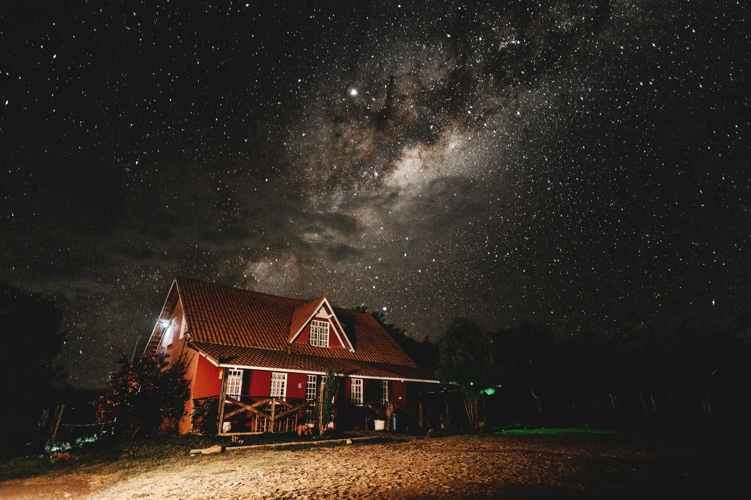 The Milky Way over a red house at night