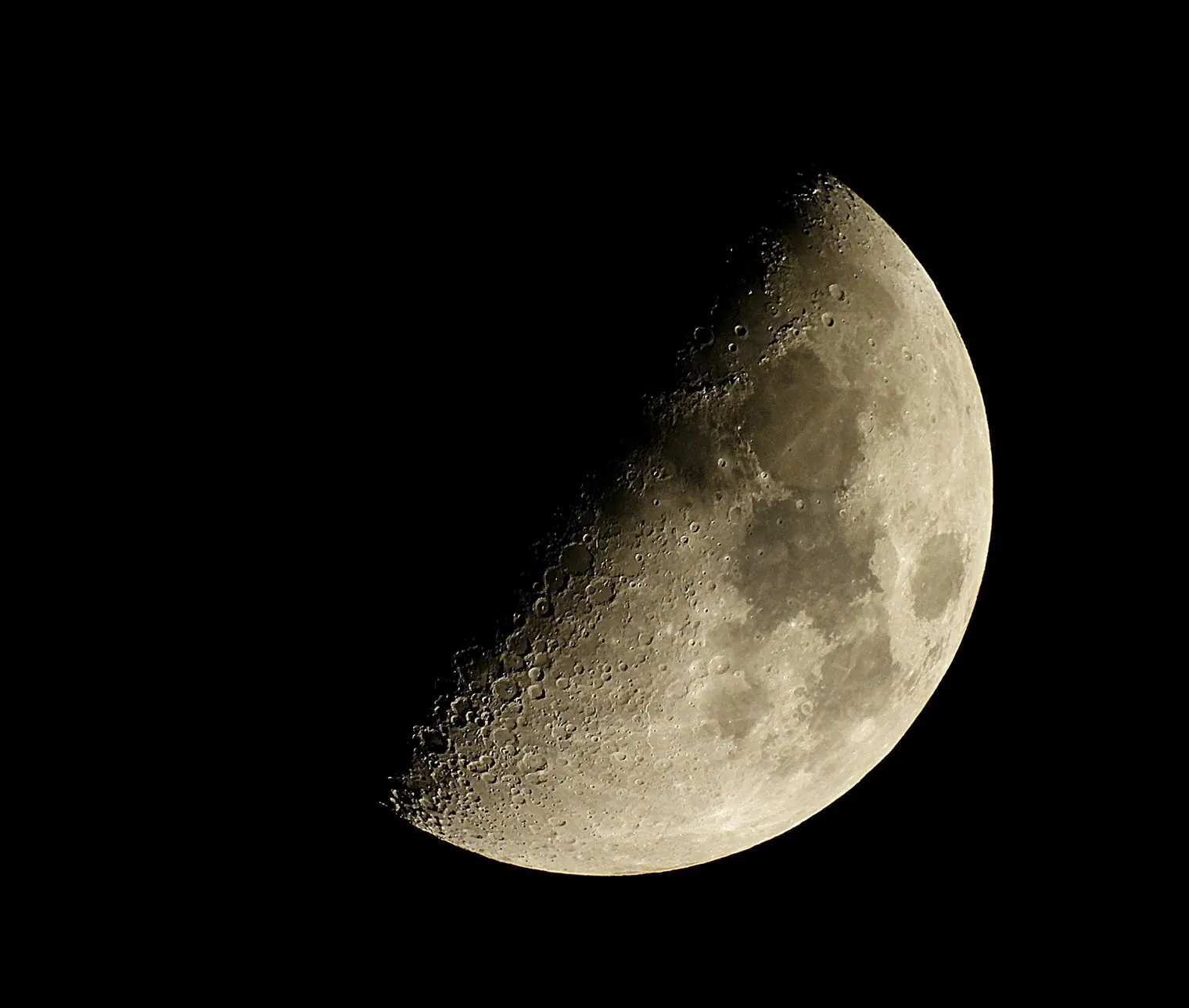 The Moon, a little more than half lit, against a black sky