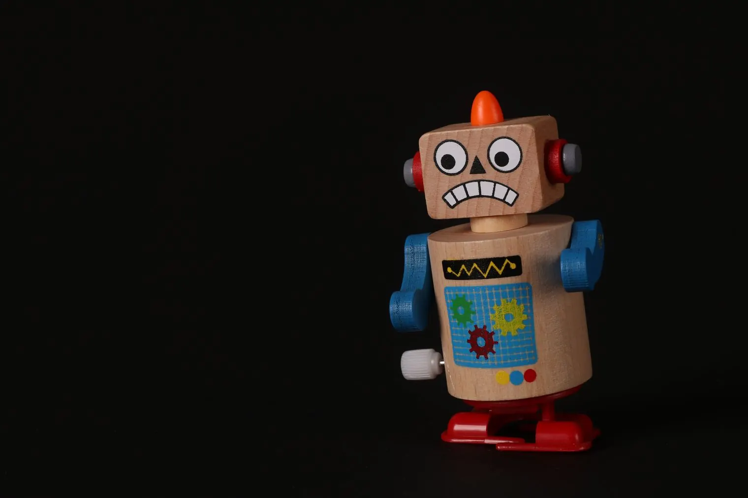 A wooden wind-up toy robot against a dark background