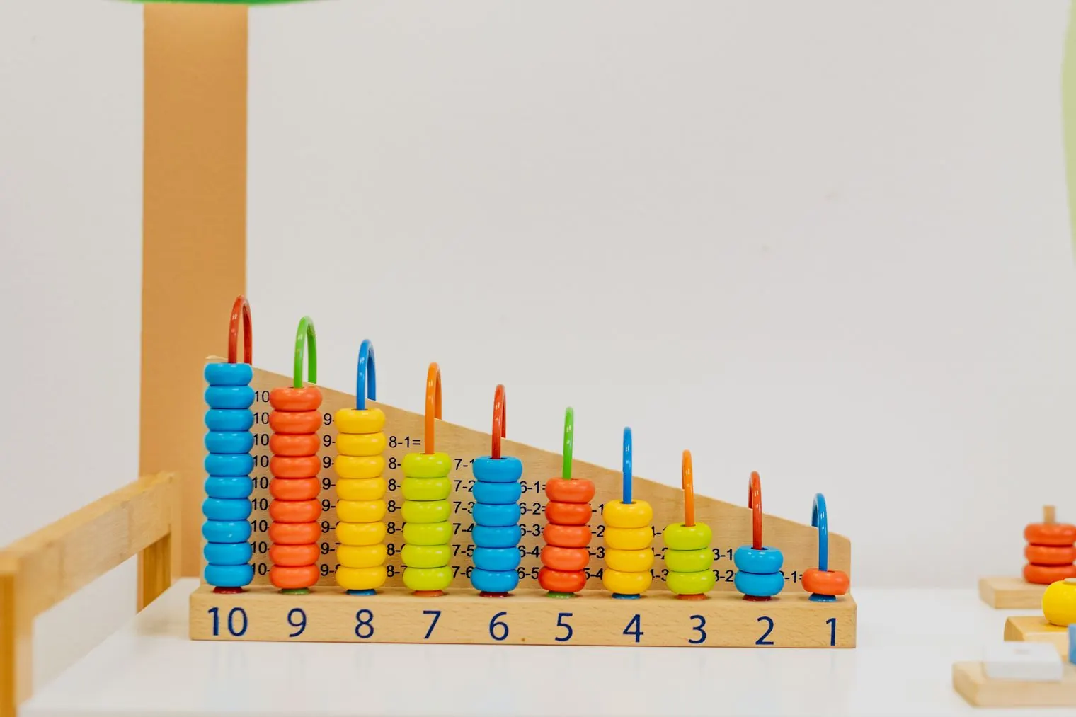 A wooden counting board with colored beads in columns from 10 down to 1